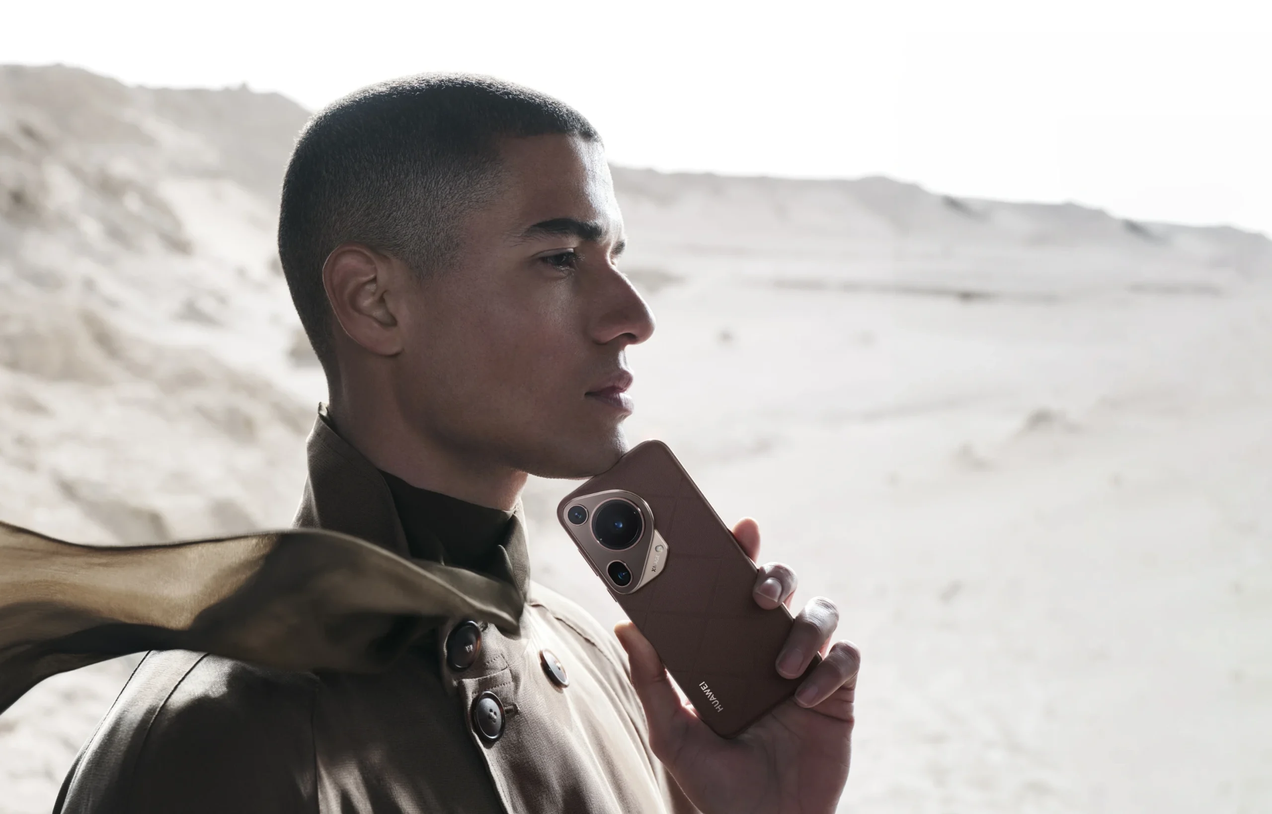 A man holding Huawei Pura 70 Ultra Brown color in desert